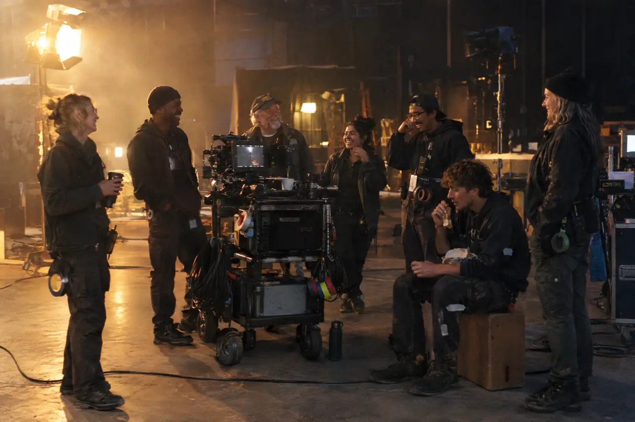 A film crew gathers around a camera cart at the end of a long shoot day on a soundstage